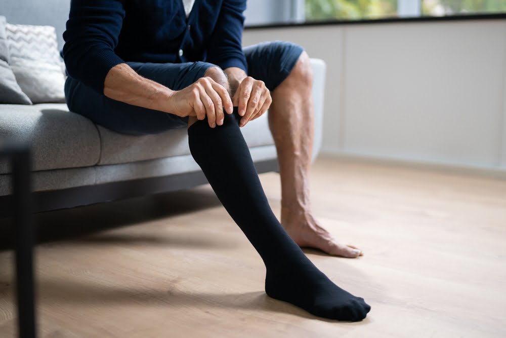 Man putting on compression stocking for varicose veins