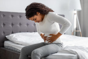 patient experiencing abdominal pain sitting on bed seeking relief