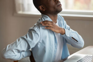 patient experiencing neck and back pain while working at desk