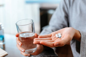 MVM Health patient holding medication pills and glass of water for pain management