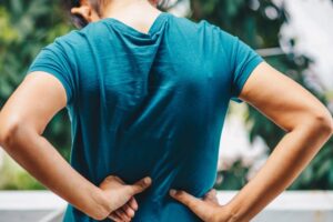 patient experiencing lower back and sciatica pain holding their back