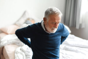patient experiencing acute lower back pain while sitting on bed at home