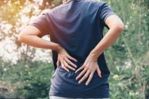 patient holding lower back in pain while outdoors seeking treatment