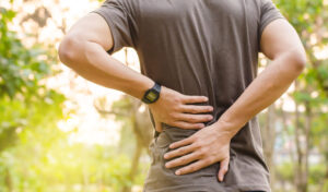patient holding lower back in pain during outdoor activity