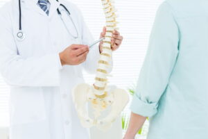 MVM Health doctor explaining spine condition to patient using anatomical spinal model