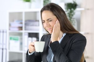 Woman suffering from jaw pain and TMJ disorder at work