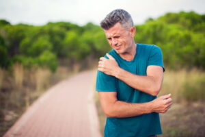 man suffering from acute shoulder pain outdoors