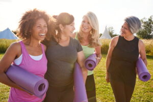 Women enjoying outdoor fitness activity with yoga mats