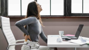 Women is suffering from back pain setting on char at her wrok place