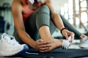 woman is sitting and holding her feat as she is suffering from Beyond the Scalpel