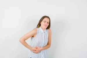 woman is holding her stomach as she is shuffering from Upper Back Stomach Pain