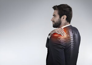 man is holding his shoulder as he is suffering from shoulder pain