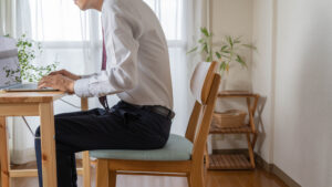 man is sitting on his working desk in a wrong Posture